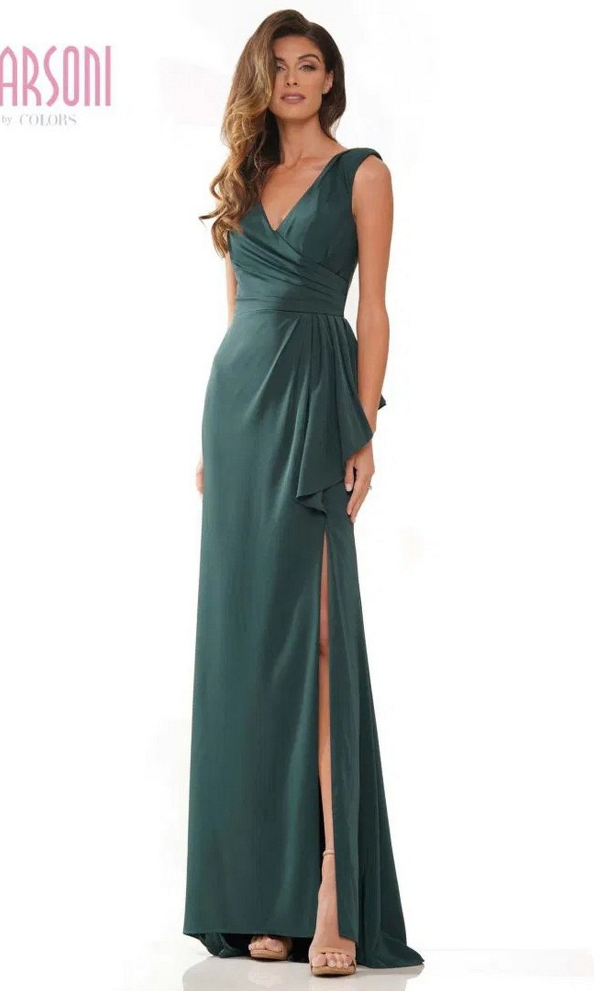 A woman wears the Marsoni MV1227 long formal dress in deep green, featuring a sleeveless design, floor-length sheath silhouette, wrap-style ruched bodice, and high slit as she stands against a white background.
